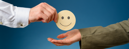 Uma mao entregando um emoji sorrindo para outra mao, simbolizando o fidelizar clientes no laboratorio